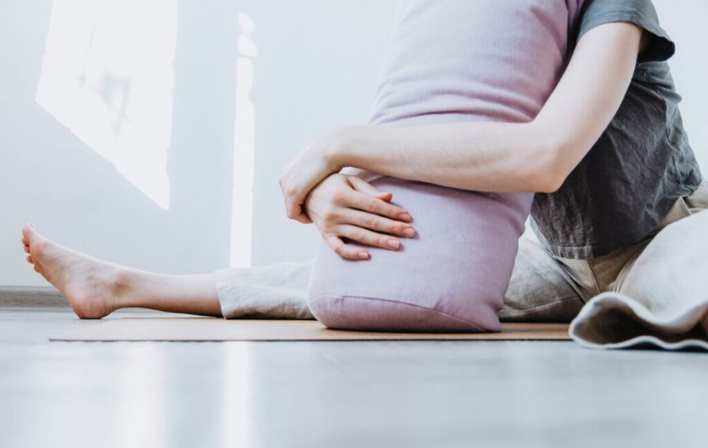 Woman in a restorative position on a yoga bolster