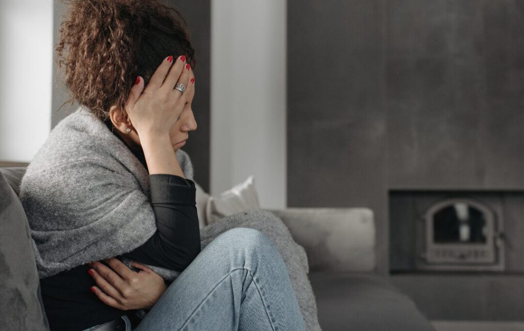 Woman sitting on a sofa with her head in her hands.